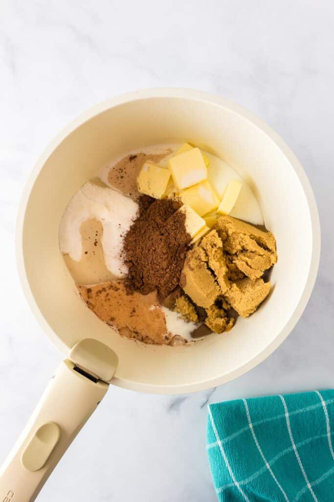 A saucepan full of butter, sugar, brown sugar, cocoa and milk before heating.