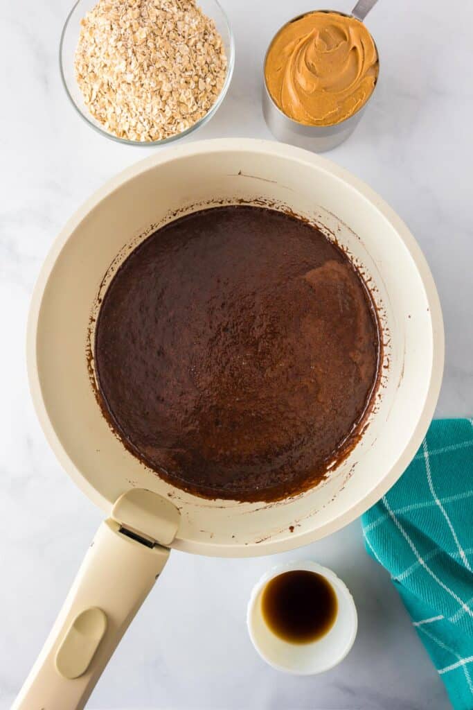 A saucepan full of liquidy chocolate no bake cookie mixture before adding oats and peanut butter.