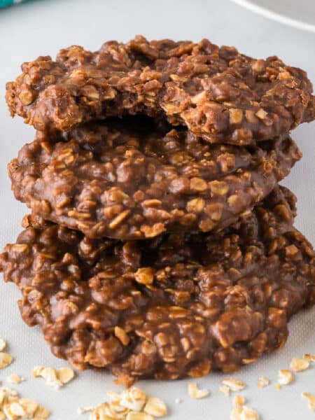 Stack of three chocolate peanut butter oatmeal cookies, with a bite taken out of the top cookie on a counter.