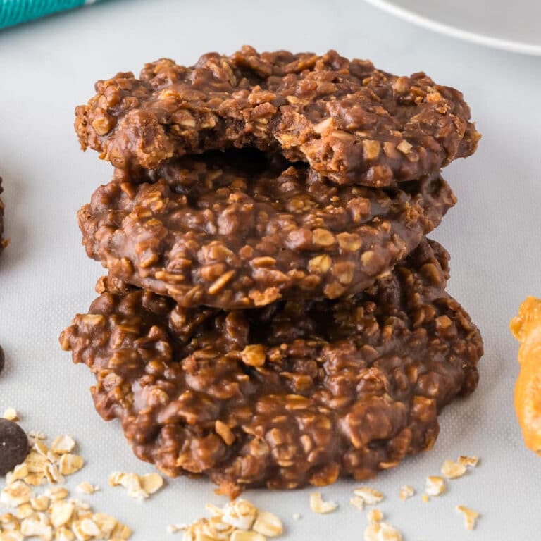 Stack of three chocolate peanut butter oatmeal cookies, with a bite taken out of the top cookie on a counter.