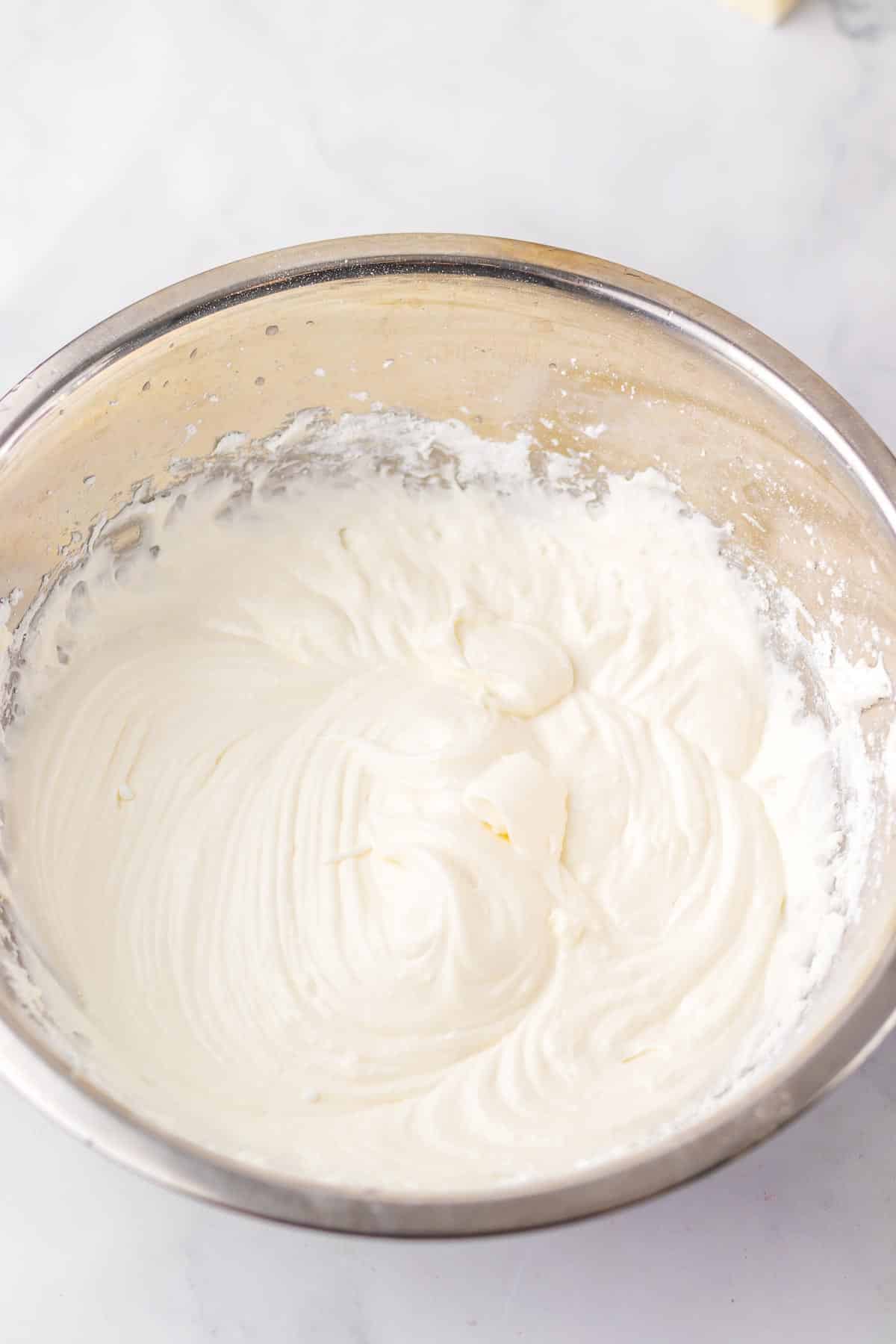 A mixing bowl filled with a marshmallow filling after being whipped with an electric mixer.