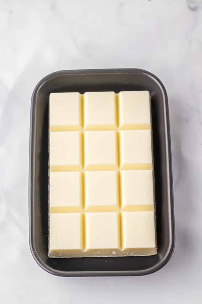 A gray baking dish full of a block of vanilla almond bark before melting.