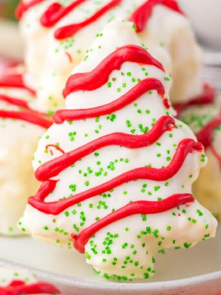 A close-up of copycat Little Debbie Christmas cake covered in white chocolate with red frosting drizzles and green sprinkles.