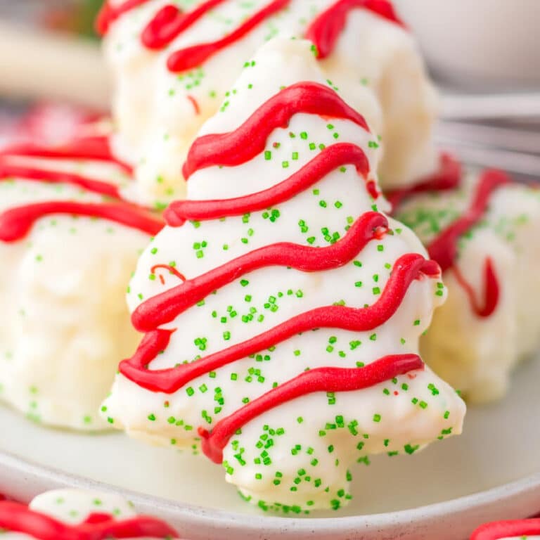 A close-up of copycat Little Debbie Christmas cake covered in white chocolate with red frosting drizzles and green sprinkles.