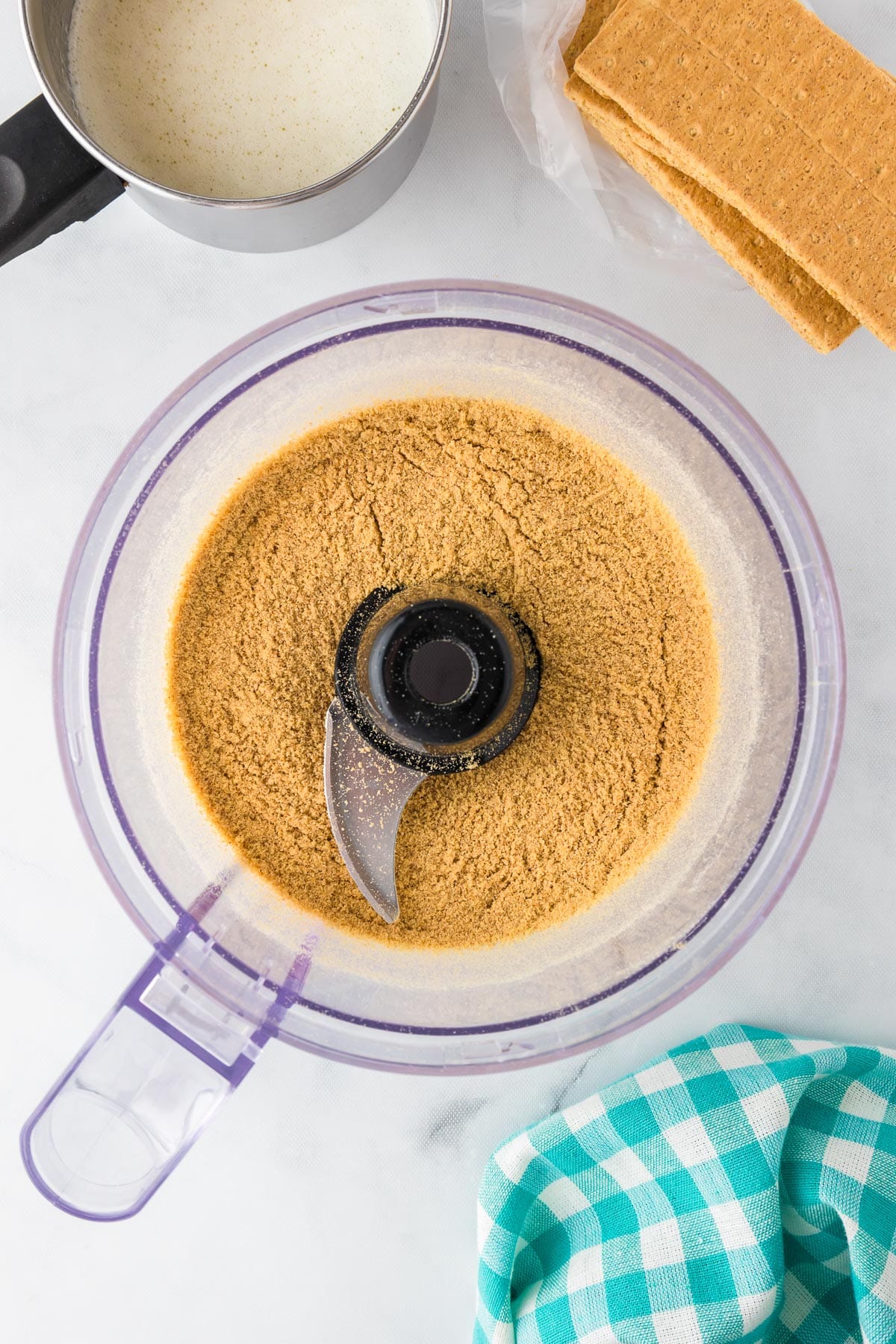 The base of a food processor full of graham cracker crumbs after grinding.