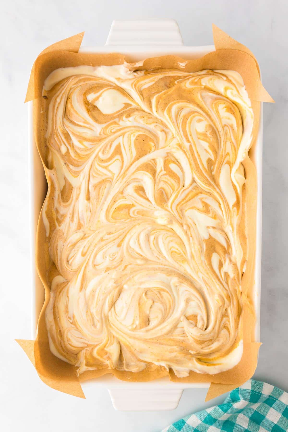 A pan full of pumpkin and cheesecake swirled ion the pan before baking.