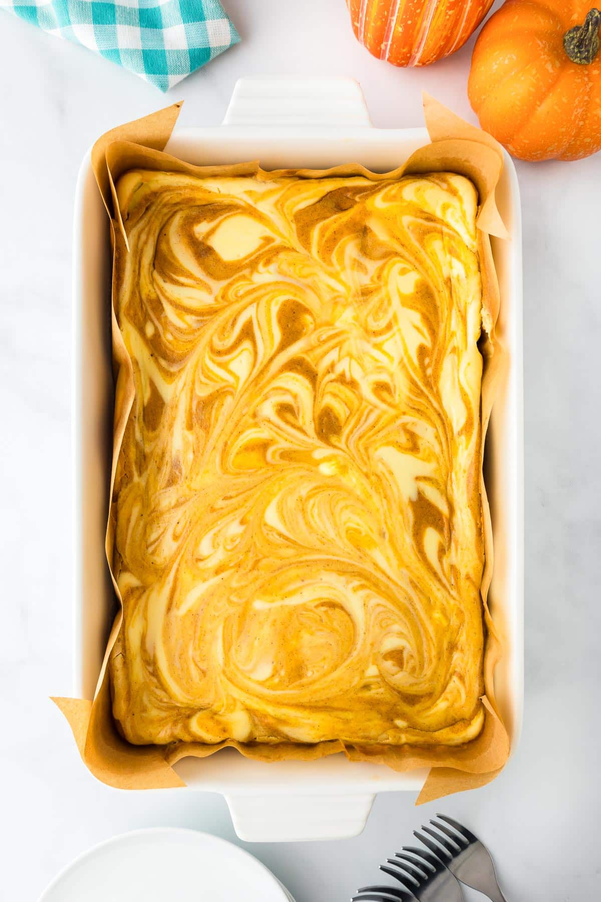 A baking dish full of swirled pumpkin cheesecake bars after baking.