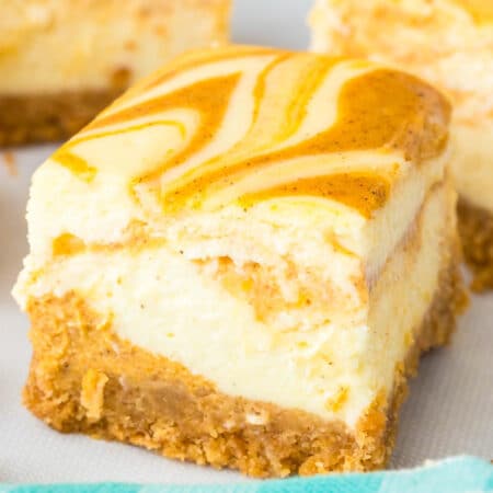 Close view of a pumpkin swirl cheesecake bar with a few more bars in the background.