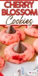 Close-up of pink cherry blossom cookies topped with chocolate kisses on a baking tray with title text across the top of the image.