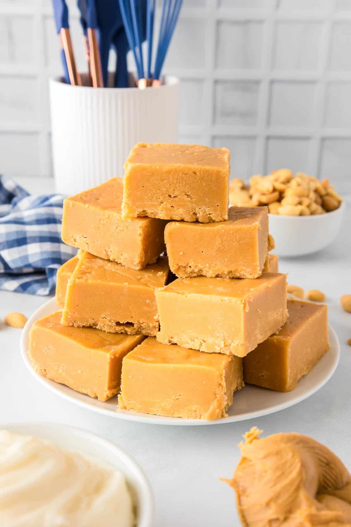 A plate stacked with pieces of 2 ingredient peanut butter fudge on a kitchen counter.