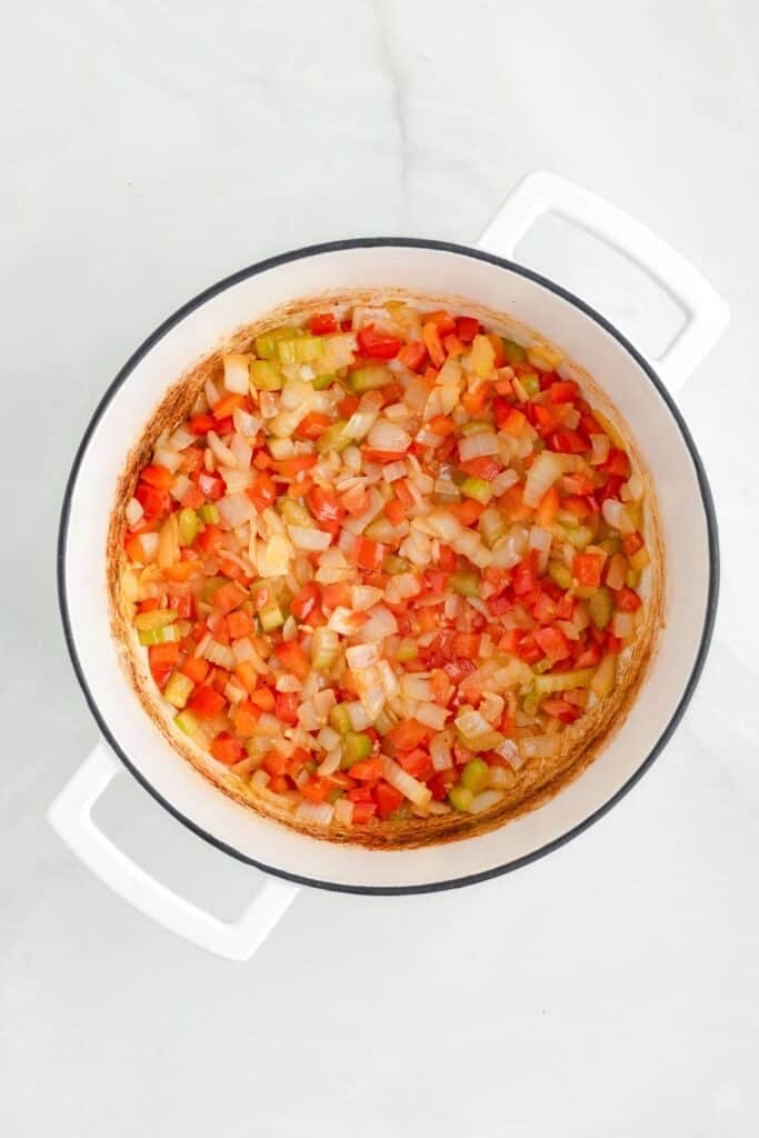 A pot containing a mixture of chopped onions, celery, and peppers after sauteeing for chicken corn chowder.