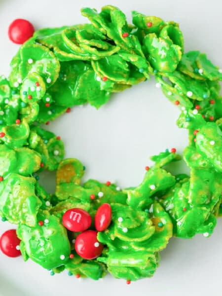 Square view of a green Christmas wreath cookie decorated with mini red M&Ms and sprinkles.