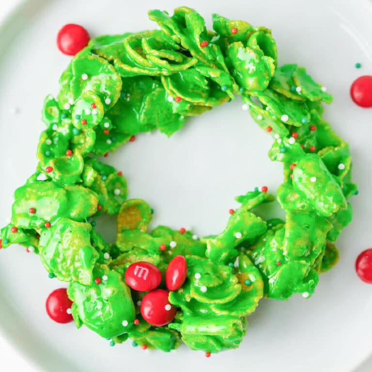 Square view of a green Christmas wreath cookie decorated with mini red M&Ms and sprinkles.