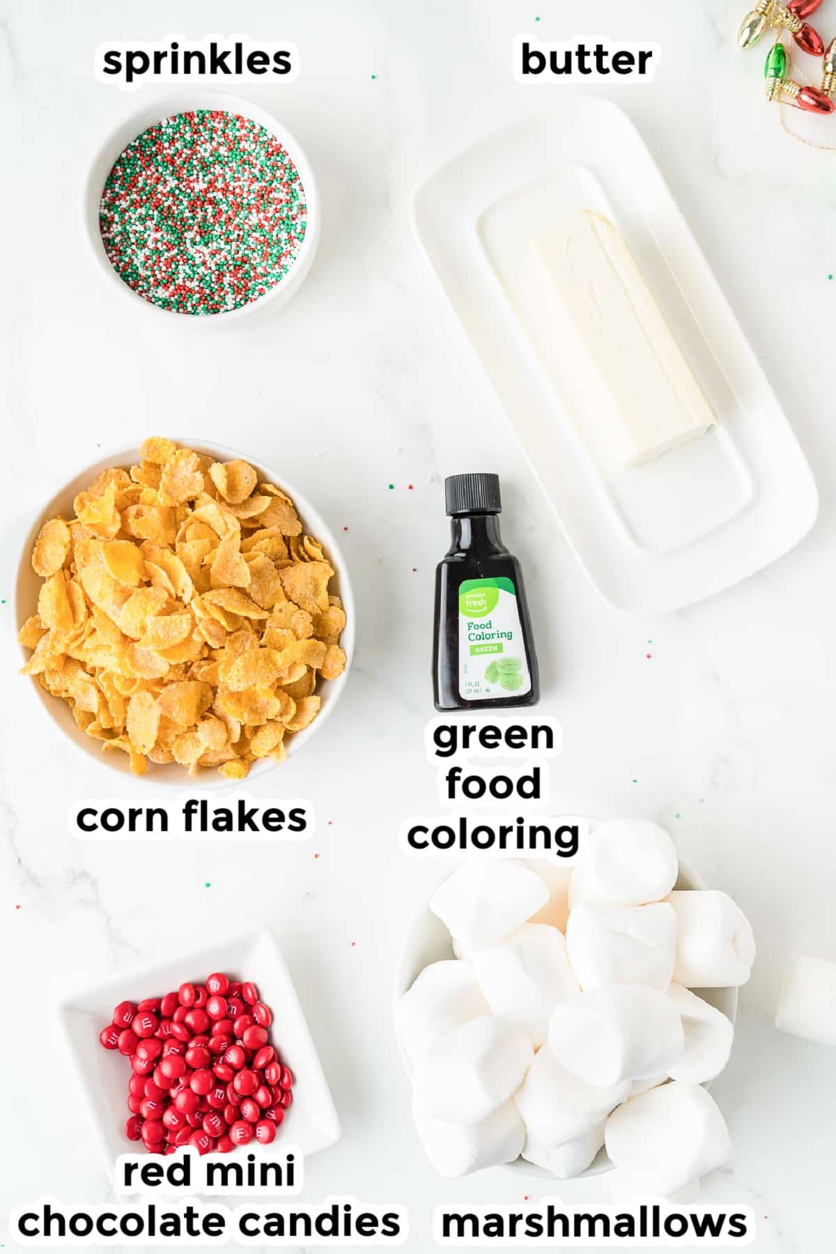 Ingredients for Christmas corn flake wreath cookies in bowls on a counter with text labels.