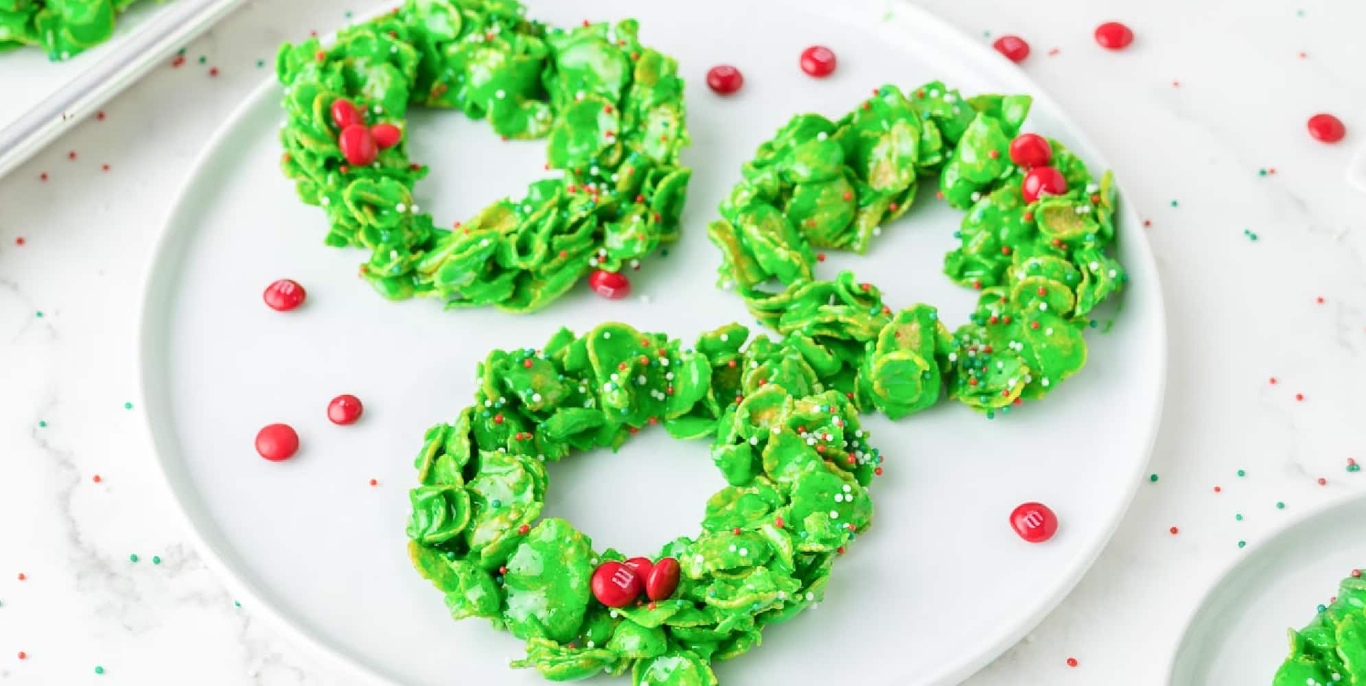 Wide view of three Christmas cornflake cookies on a plate on a counter.