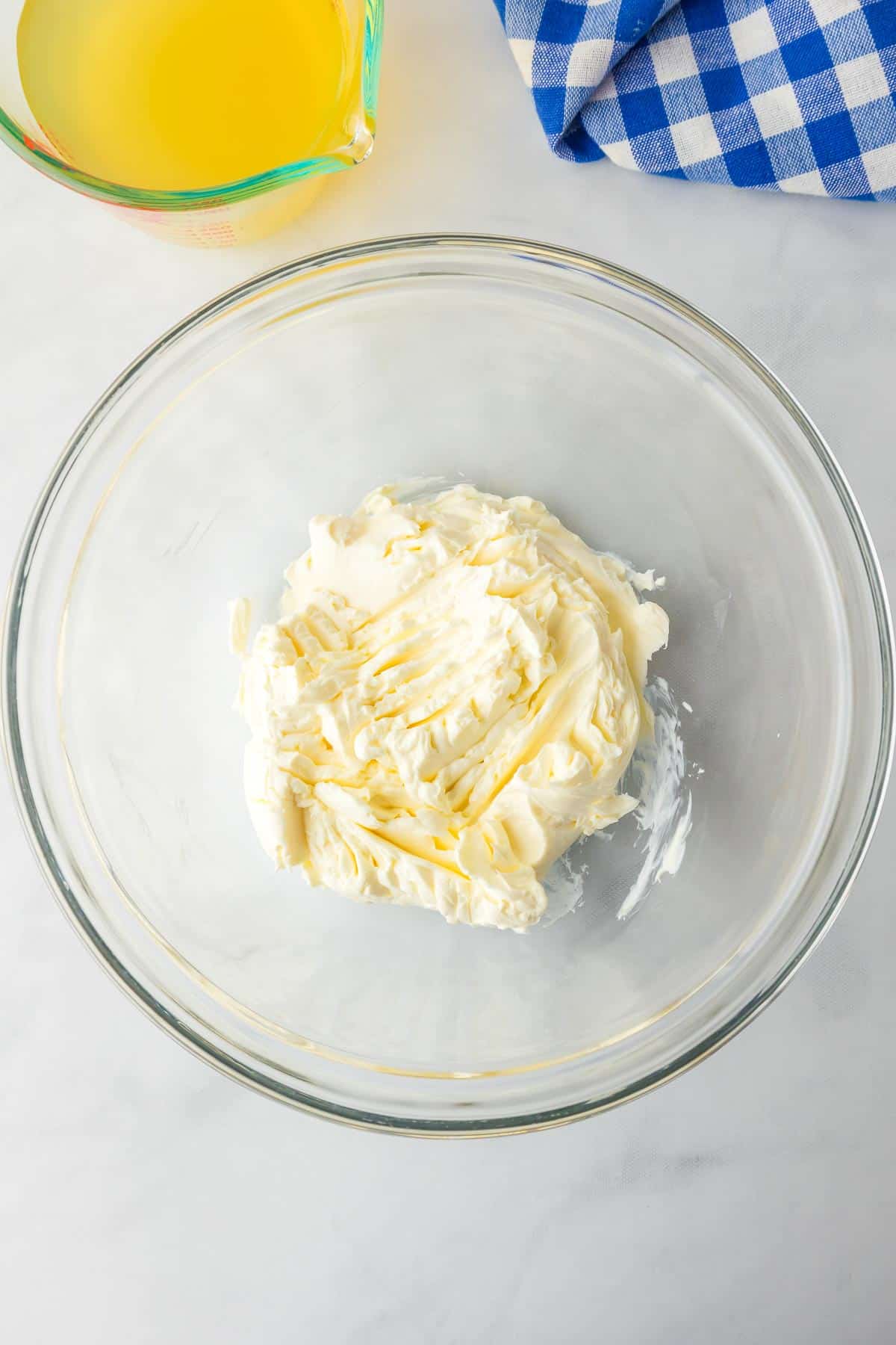 A glass bowl with creamy cream cheese on a counter for hash brown potato soup.