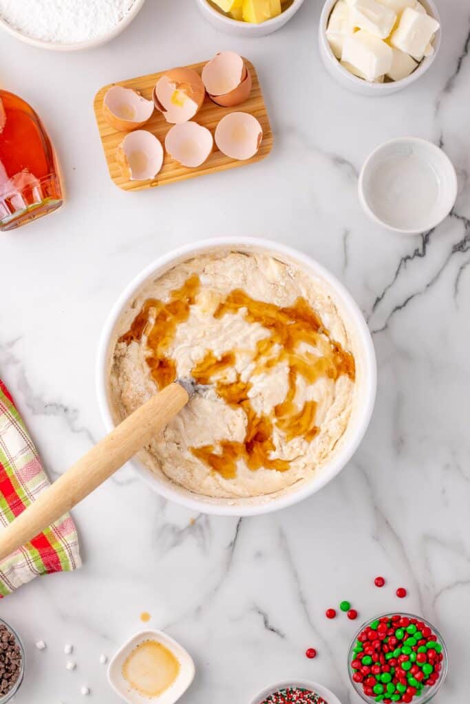 Wet ingredients including egg whites and maple syrup being mixed into the dry ingredients in a bowl for elf cupcakes.