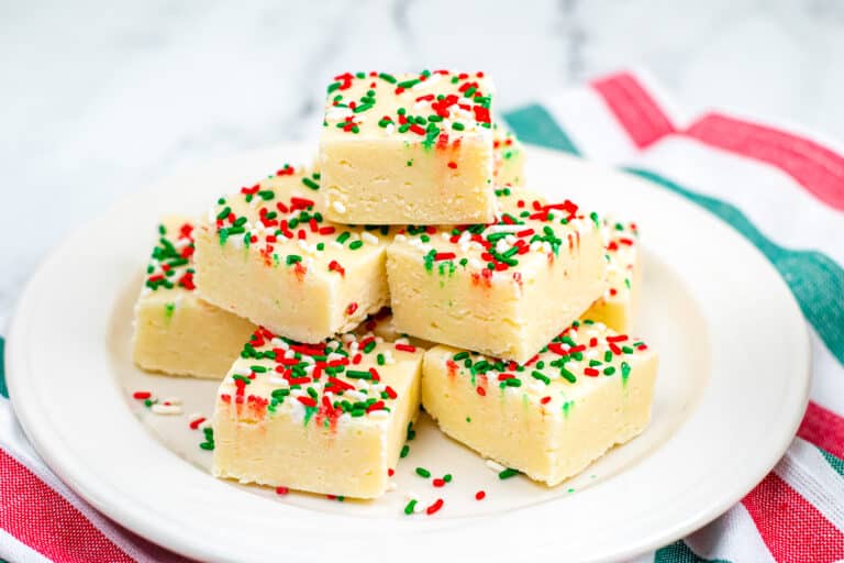 Wide view of vanilla fudge topped with Christmas sprinkles on a plate.