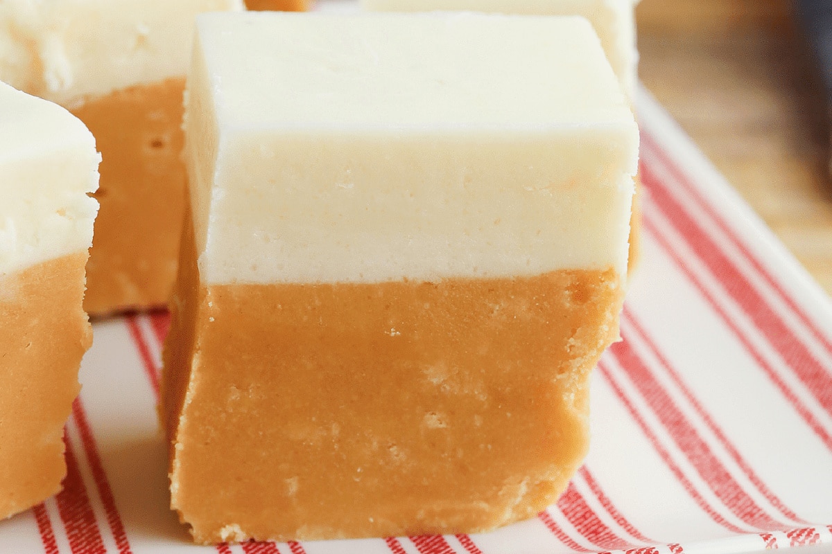 Close-up of a two-layered butterbeer fudge square on a red-striped plate.