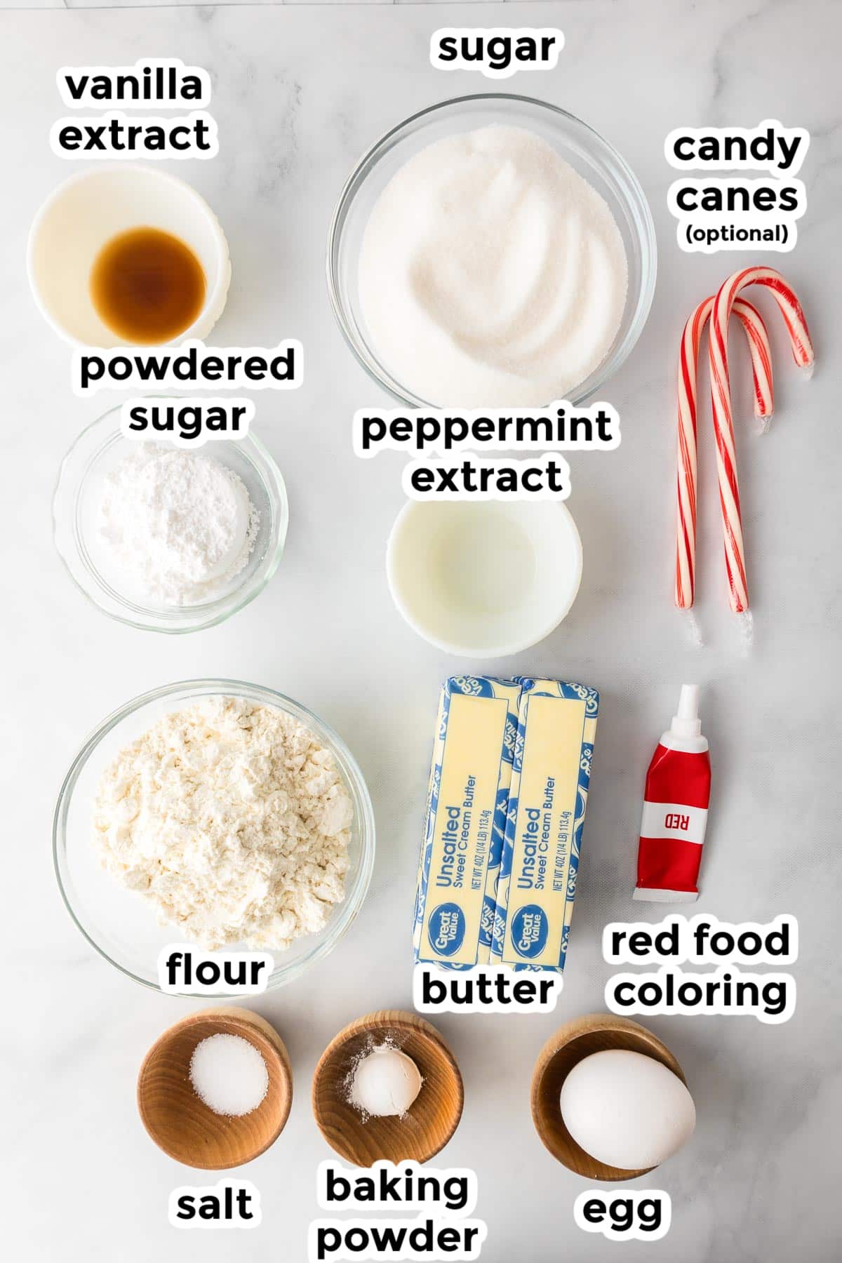 Ingredients for candy cane cookies in bowls on a counter with text labels.