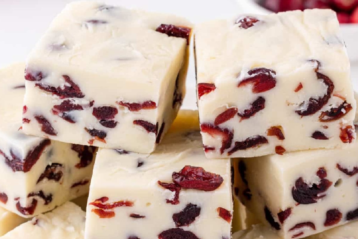 Pieces of white chocolate cranberry fudge stacked on a plate.