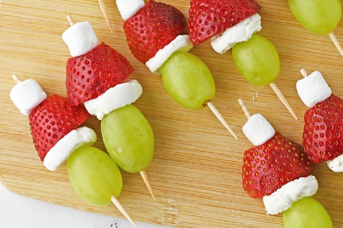 Fruit skewers with strawberries, green grapes, and marshmallows made to look like the Grinch.