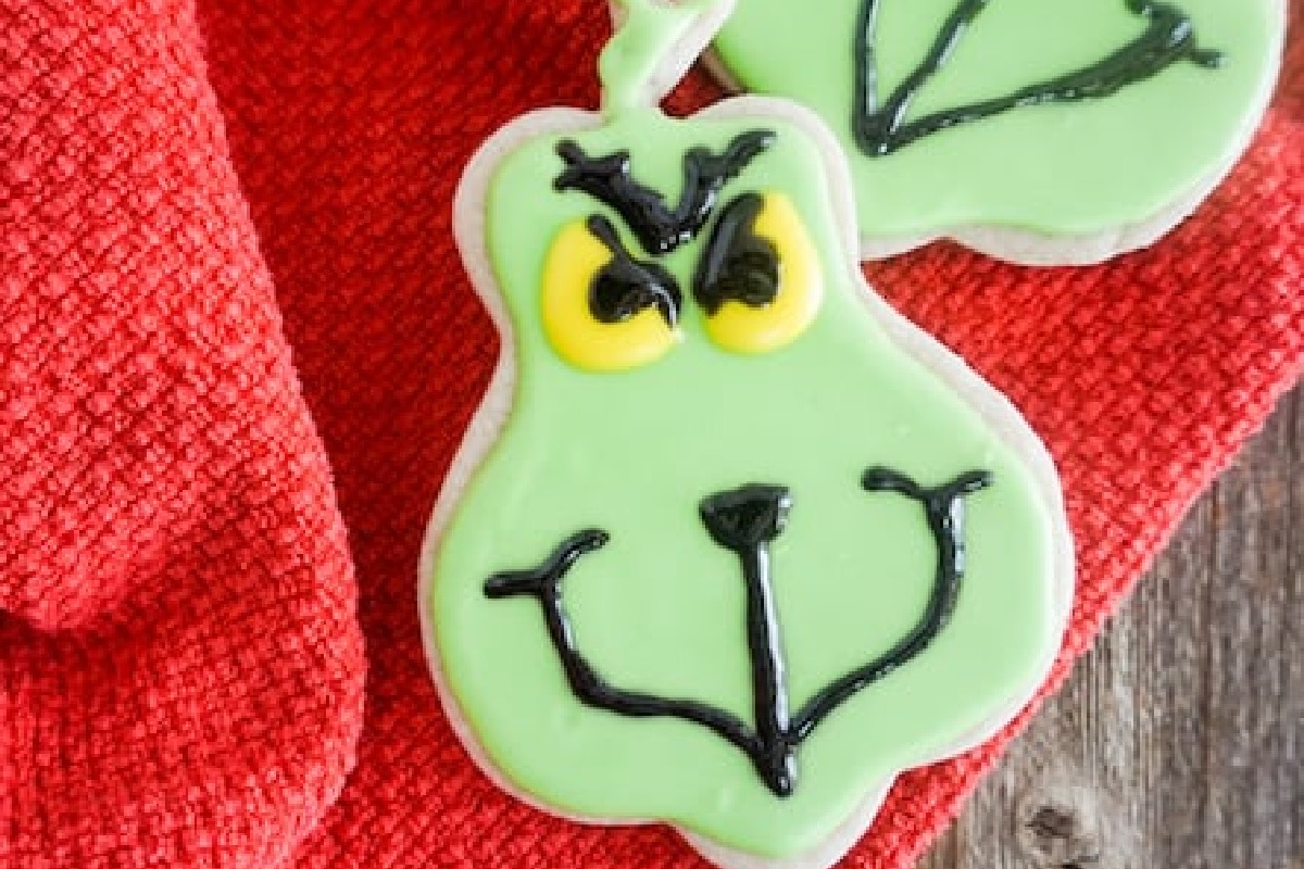 Green grinch cookies decorated with an angry, grinning face on a cloth.