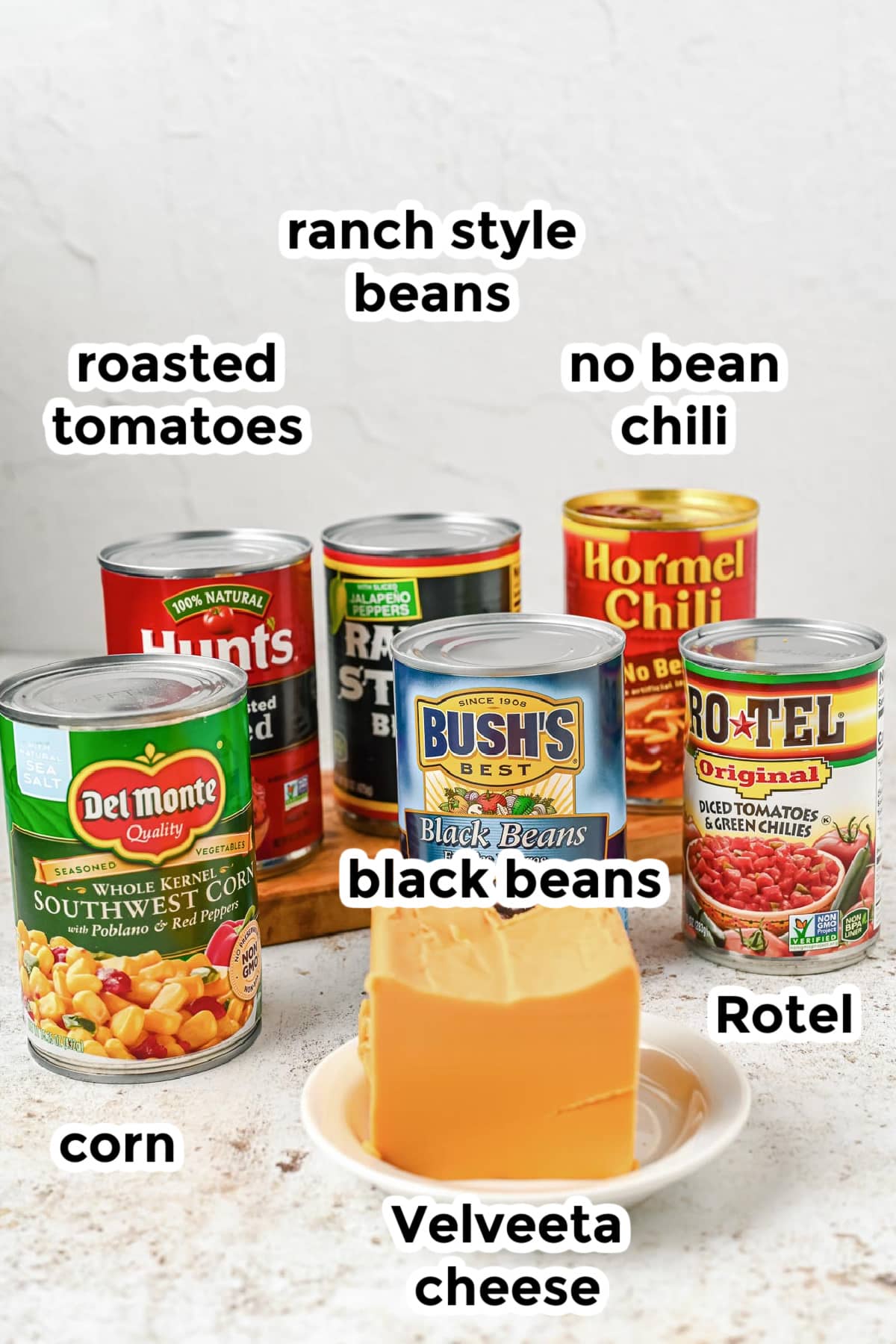 Ingredients for 7 can soup in cans except the Velveeta cheese which is on a plate.