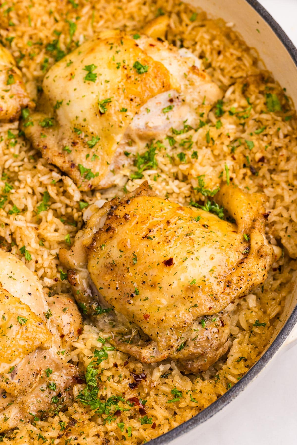 A close-up of cooked brown chicken thighs and rice in the pan.