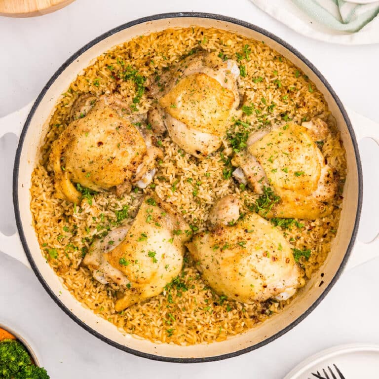 A square view of a pot with cooked chicken thighs and rice.