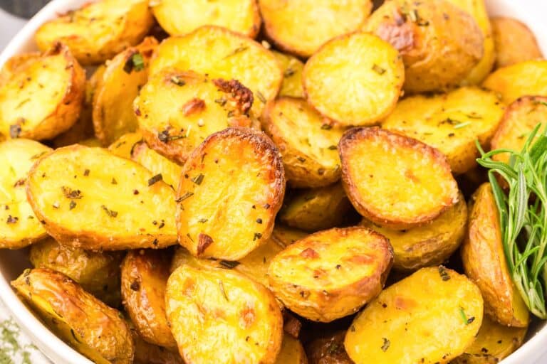 A bowl of roasted baby potato halves seasoned with herbs close up in a bowl.