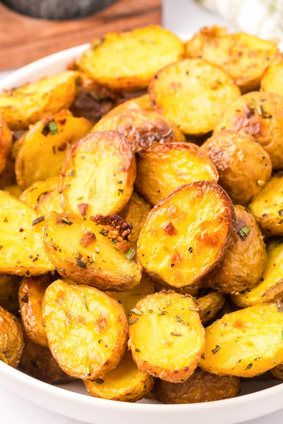 A pile of golden brown roasted baby potatoes piled high in a bowl from the side.