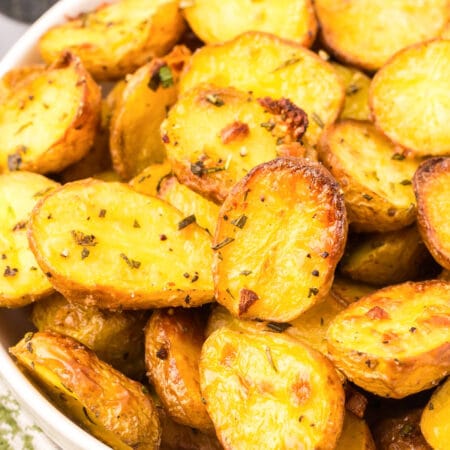 A bowl filled with seasoned and roasted baby potato halves, golden and crispy close up.