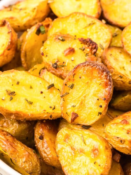 A bowl filled with seasoned and roasted baby potato halves, golden and crispy close up.