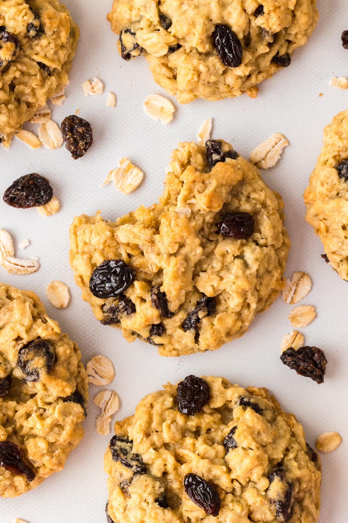 Oatmeal raisin cookies on a white counter close up with one cookie missing a bite.