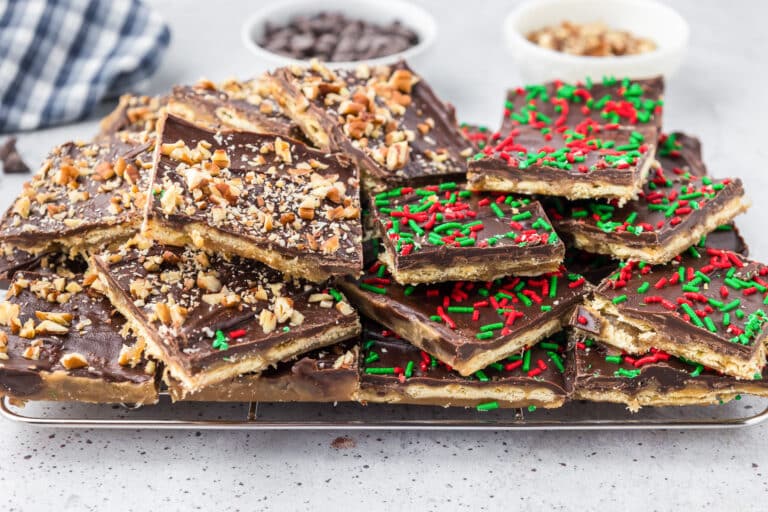 A pile of chocolate toffee bark with nuts and colorful sprinkles sits on a wire rack.