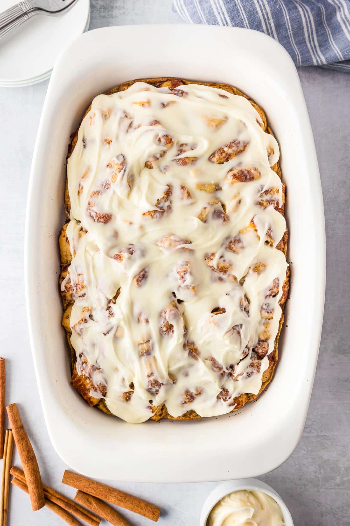 A rectangular dish filled with frosted cinnamon roll casserole.