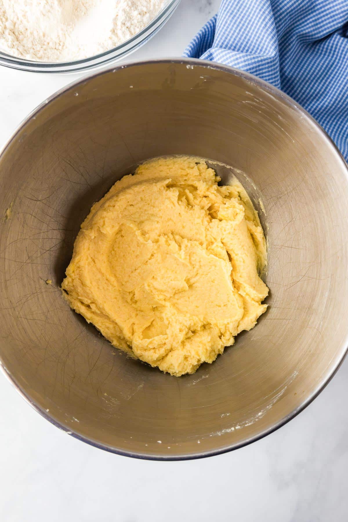 Wet ingredients in a mixing bowl for snickerdoodle cookie bars with dry ingredients in a bowl nearby on a counter.