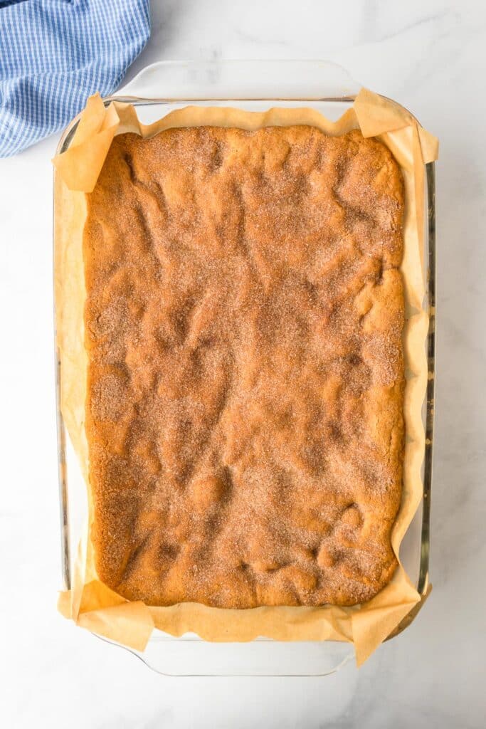 Snickerdoodle cookie bars in a parchment lined pan after baking.