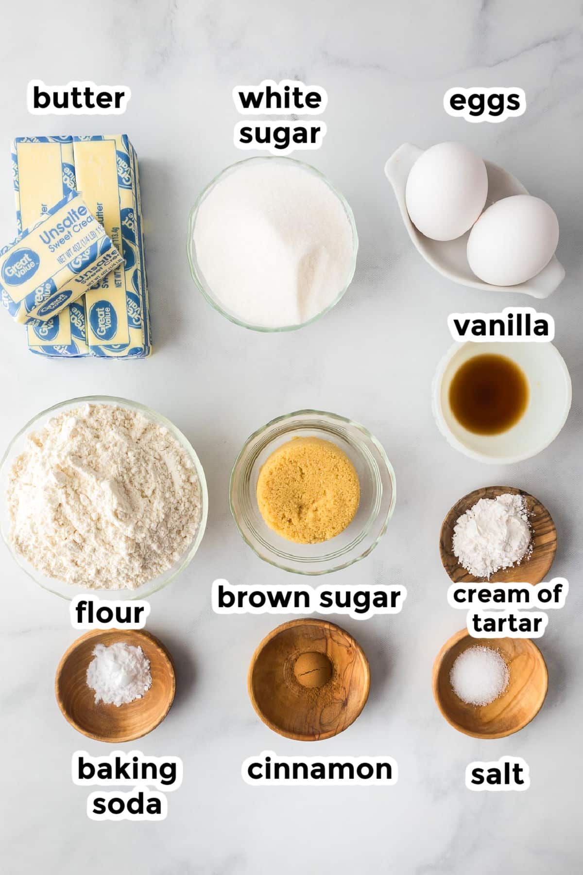 Ingredients for snickerdoodle cookie bars on a counter in bowls with text labels.