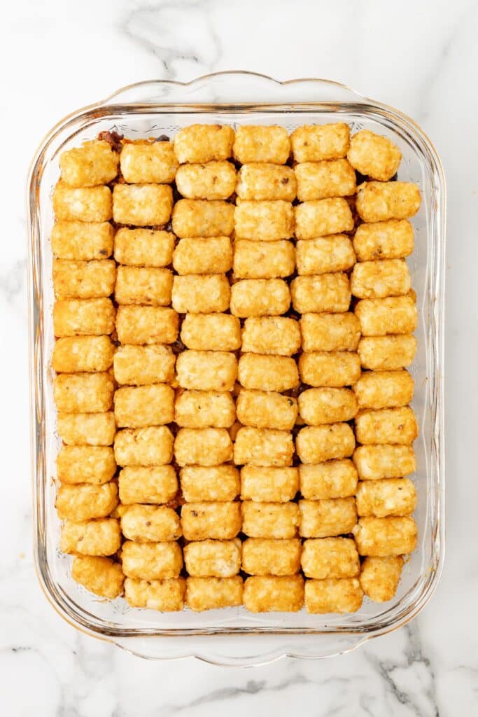 A baking dish filled taco tater tot casserole on a counter with evenly arranged tater tots after baking.