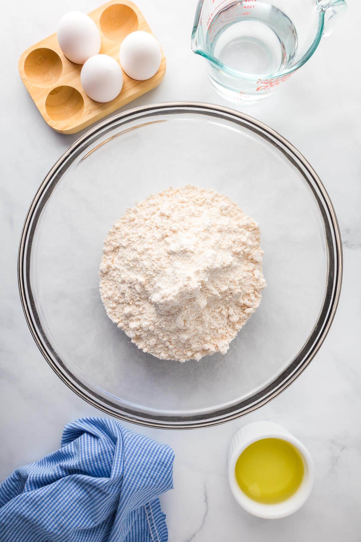 A bowl of cake mix with water, eggs and oil on the counter nearby for banana pudding poke cake.