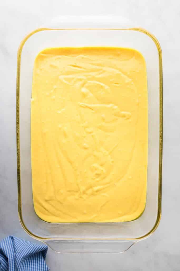 A glass casserole dish full of yellow cake batter for banana pudding poke cake.