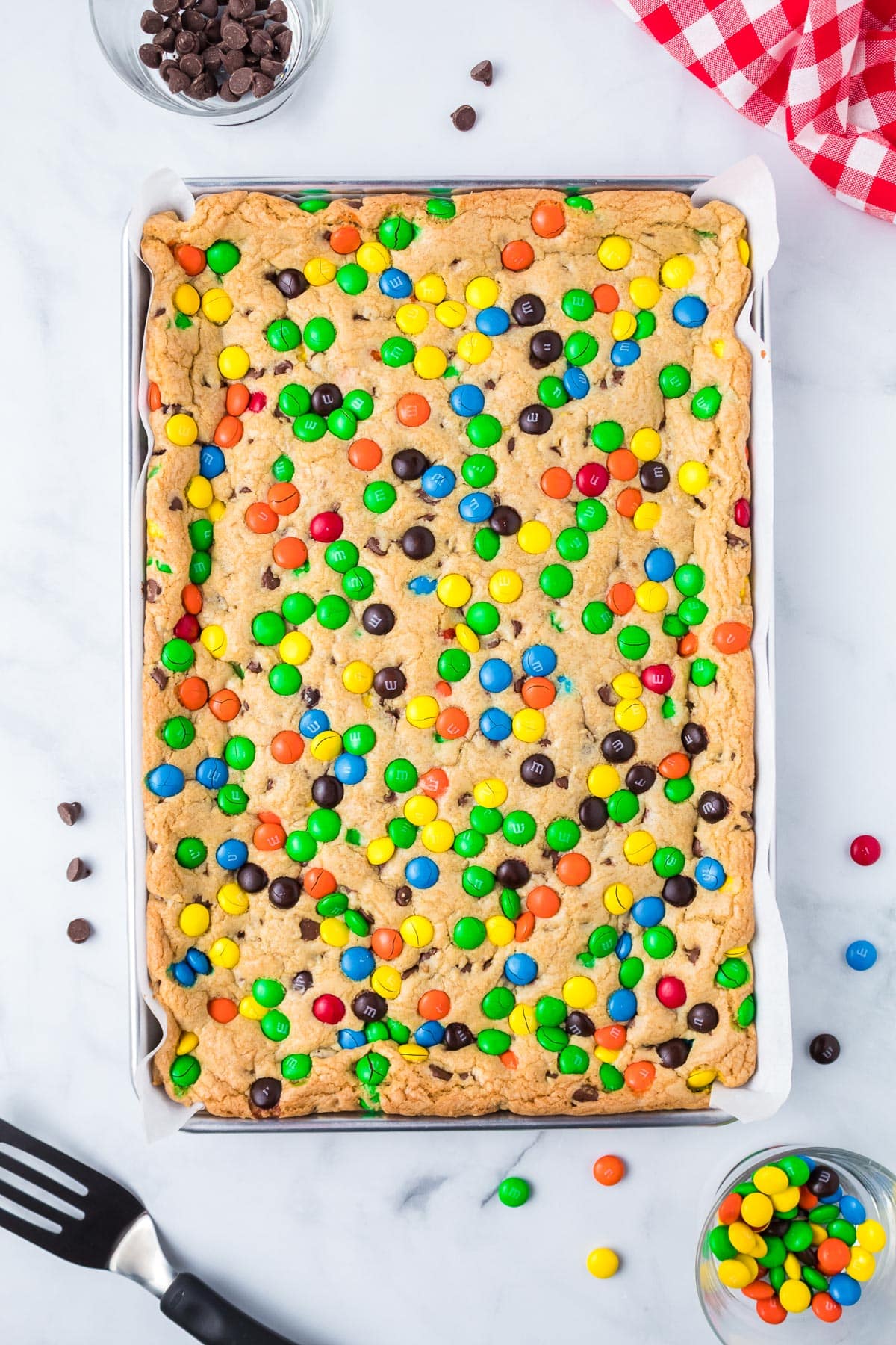 Baked M&M cookie bars in a baking sheet from above after baking.