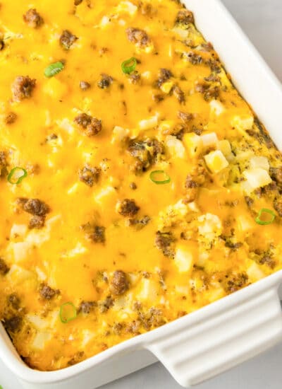 Square view of a casserole dish with sausage potato breakfast casserole topped with cheese after baking.