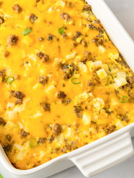 Square view of a casserole dish with sausage potato breakfast casserole topped with cheese after baking.