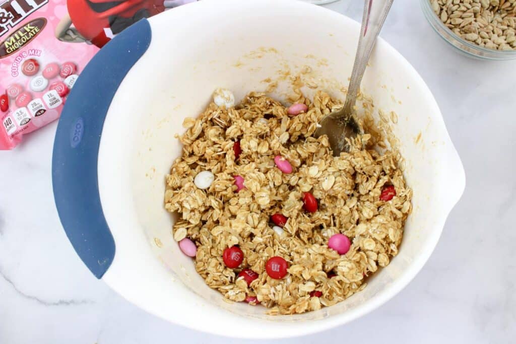 A bowl with and oatmeal snack bite dough mixture being stirred with a spoon.