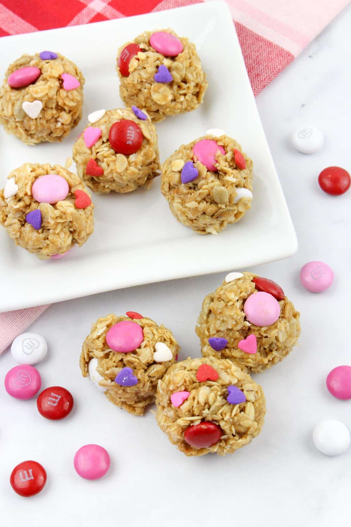 Oatmeal snack balls with pink, red, and purple chocolate candy and heart sprinkles on a plate.