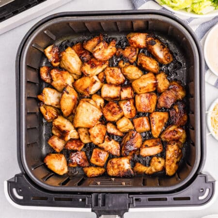 Cooked airfryer chicken bites in an air fryer basket from above.