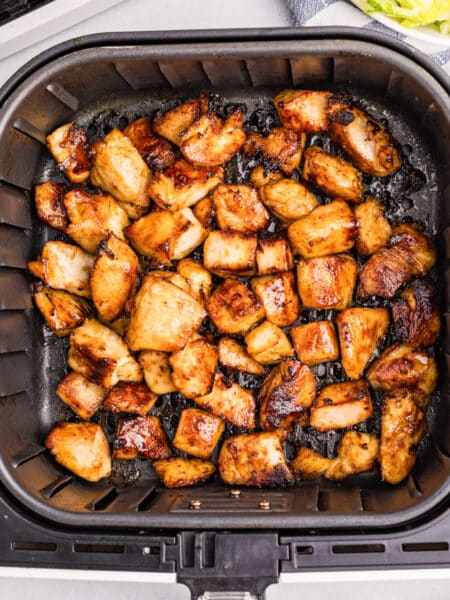 Cooked airfryer chicken bites in an air fryer basket from above.